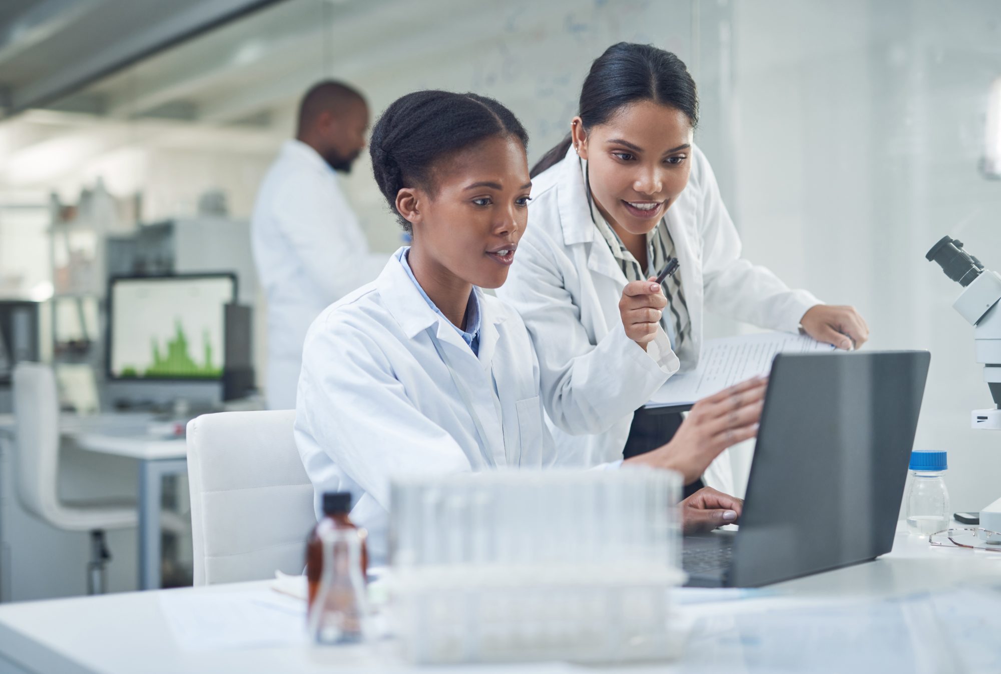 Two young female scientists using a laptop in a laboratory